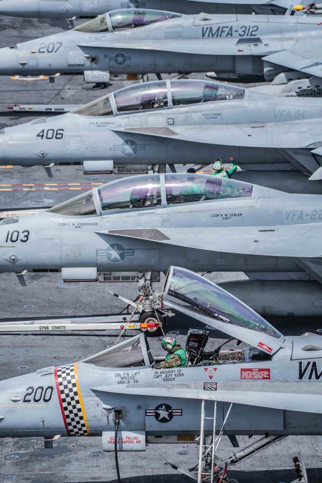A Marine inspects the flight controls of an F/A-18 Hornet, assigned to the Checkerboards of Marine Strike Fighter Attack Squadron (VMFA) 312, on the flight deck aboard the aircraft carrier USS Theodore Roosevelt (CVN-71)