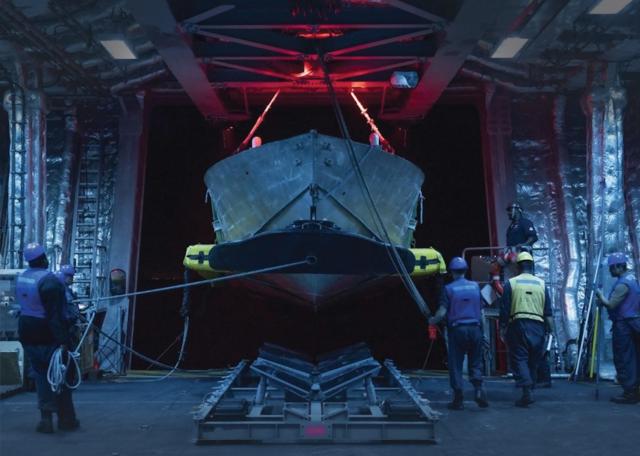 Sailors practice mine countermeasures unmanned surface vessel launch and recovery in the  mission bay of the Independence-variant littoral combat ship USS Cincinnati (LCS-20). The Navy should develop a robust unmanned capability dedicated to mine countermeasures.