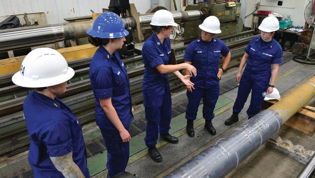 A chief warrant officer, two lieutenants, and two ensigns discuss repairs to the shaft of the USCGC Northland (WMEC-904). Developing midlevel leaders is a critical retention tool.