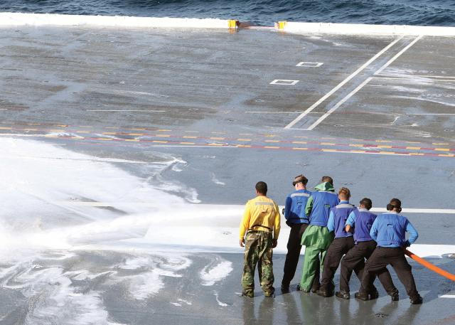 Firefighting foam is corrosive and needs to be removed from ship decks and other areas after the system is tested. The author thought he and one other sailor could spray down the deck, in the dark, during heavy seas. His mistake put their lives in danger.