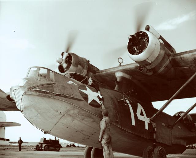 A veteran pilot of Navy Patrol Bombing Squadron (VPB) 63 gets last-minute direction before taking off on a patrol during World War II. The U-boat silhouette in front of the cockpit signifies the plane was credited with sinking an enemy submarine.