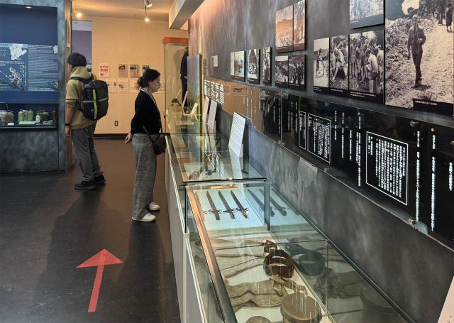 Museumgoers view an exhibit showing artifacts excavated from the tunnel complex and describing the battle.