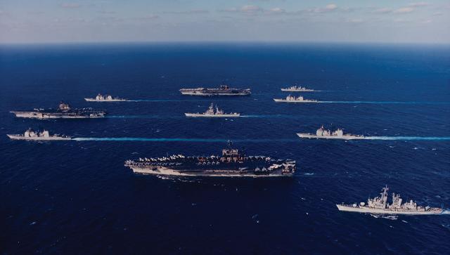 Ten ships of Task Force 155 gather during Operation Desert Storm. Leading the formation at left is the USS Saratoga (CV-60), flanked by the San Jacinto (CG-56), top, and Thomas Gates (CG-51). At center is the USS Mississippi (CGN-40), flanked by the America (CV-66), top, and John F. Kennedy (CV-67). At rear are, from top, the USS Preble (DDG-46), Philippine Sea (CG-58), Normandy (CG-60), and William V. Pratt (DDG-44).