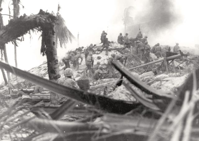 Some who have survived the cauldron of the beach gain ground as the bloody struggle continues; the determined Japanese defenders will fight almost to the last man.