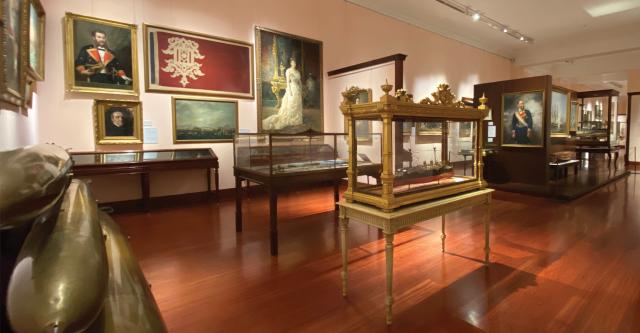 (Below) An exhibition room with 19th-century paintings, artifacts, and ship models.