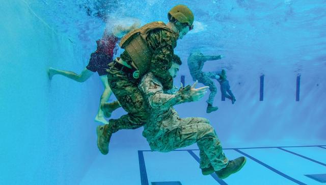 Marines with Marine Corps Water Survival School (MCWSS) practice rescue techniques. MCWSS trains Marines and sailors to be instructors of water survival, a program that should be expanded so every unit has a billet responsible for year-round water training.