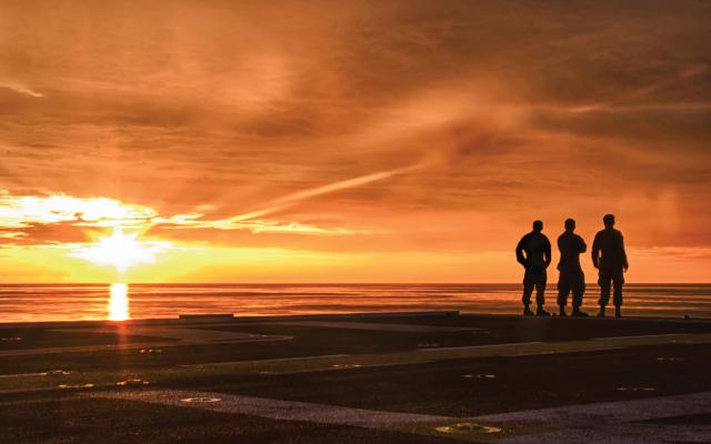 Three Marines  take a moment to  experience a calming end to the day  on board the USS Peleliu (LHA-5) in  the Red Sea, 2013.