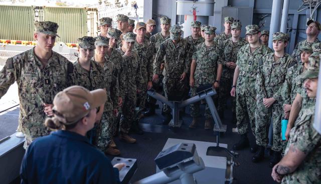 A boatswain’s mate addresses junior surface warfare officers attending the nine-week-long Basic Division Officer Course (BDOC) as they tour the USS Makin Island (LHD-8). The Navy should revamp SWO training into a single, longer training to allow more material to be covered.