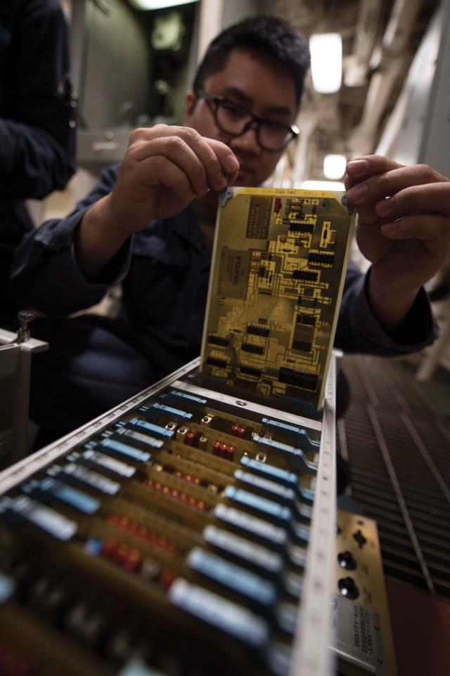 Sailor performing maintenance on an integrated electrical circuit 