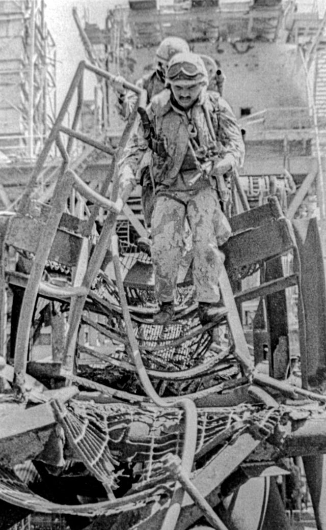 Lt. R. A. Bernal leads his men through the twisted metal of the Iranian oil platform Sassan, Persian Gulf, 18 April 1988.