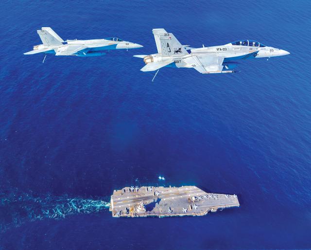 Two F/A-18 Super Hornets fly above the USS Gerald R. Ford