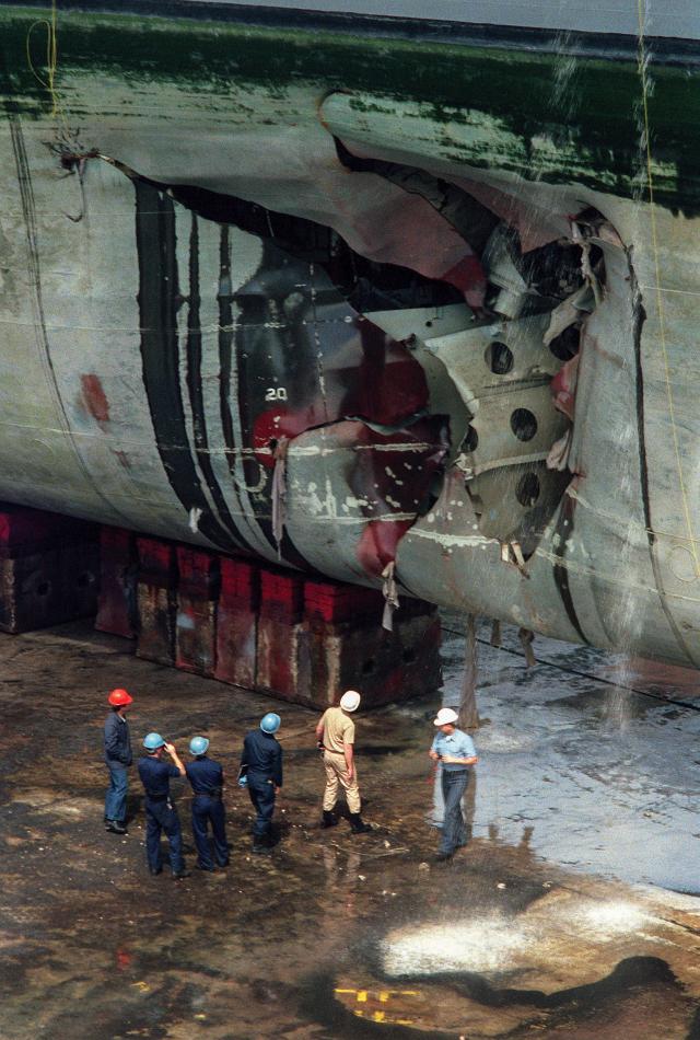 Inspectors examine mine damage to the USS Tripoli (LPH-10) in drydock in Bahrain
