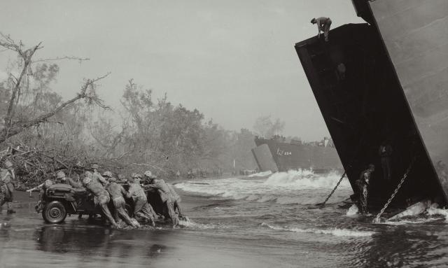 Interoperability between the Coast Guard and the Marine Corps is not new. In this photo, Marines and Coast Guardsmen push ashore a jeep from a Coast Guard-manned LST onto the beach of Cape Gloucester in 1943 as part of the New Britain Campaign. 