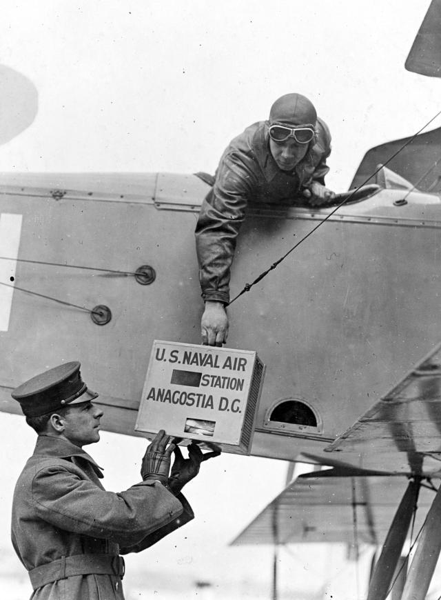 Carrier pigeons in pigeon box being handed up to pilot in plane before leaving, U.S. Naval Air Station, Anacostia, Washington, D.C. February 12, 1919.