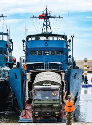 In the 2026 scenario, Chinese ships transporting weapons, troops, and equipment across the Taiwan Strait have been primary targets for U.S. submarines. Here, soldiers from the PLA 73rd Group Army unload trucks from a roll-on/roll-off vessel. 