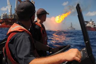 A Coast Guard small-boat crew looks on at the site of drilling operations at the Deepwater Horizon response site in July 2010. In a 2026 homeland defense scenario, dozens of offshore drilling platforms in the Gulf of Mexico could be targets of kinetic or cyber attacks, causing explosions several miles apart, each resembling the Deepwater Horizon event.