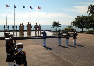 With the monument to the battle serving as a backdrop, a Philippine Marine Corps honor guard stands at attention while “Taps” is played to honor those who lost their lives during the Battle of Leyte Gulf.