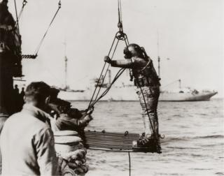 Navy divers being hoisted on board a salvage vessel 