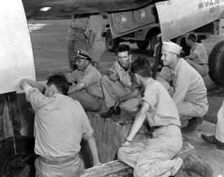 Captain William “Deke” Parsons (far right) supervises the loading of the Little Boy atomic bomb 