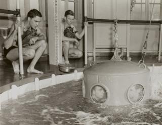 Students peer through the portholes in a diving bell