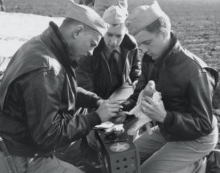 Navy officers attach a message to the leg of a carrier pigeon. The U.S. Naval Academy was the first Navy command to breed and train carrier pigeons. French professor Henri Marion built an experimental pigeon loft in an academy boathouse in 1891.