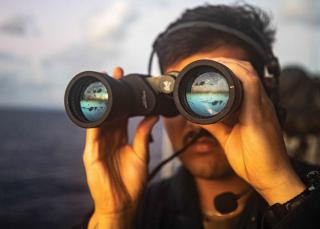 A seaman scans for surface contacts on the bridge wing as the guided-missile cruiser USS Robert Smalls (CG-62) conducts routine underway operations in the South China Sea. FONOPs aim to challenge excessive maritime claims deemed unlawful under international law, but they also are taxing the Navy’s operational resilience.
