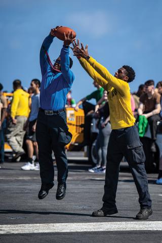 Sailors play football on the deck of the USS Nimitz (CVN-68). Much like coaches, leaders must earn the respect and trust of their teams.