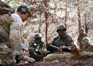 Justified Accord 2024 brought units from 23 nations together in Nanyuki, Kenya, to build readiness and multinational interoperability. Top: Members of the Tanzania People’s Defence Forces and a British Army soldier dig an observation post. Below: Kenya Defence Forces members load a simulated casualty during urban operations training. An Africa-based AfriCom could more easily collaborate and train with partner nations.