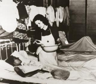 Lieutenant Nash administers care to a fellow prisoner in the Santo Tomas camp hospital