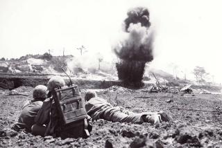 Closing in on “Sugarloaf Hill”: A 6th Marine Division demolition crew watches dynamite charges explode and destroy a Japanese cave, May 1945.