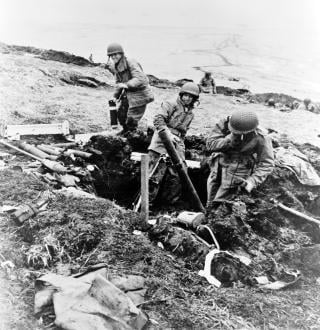 Attu, 4 June 1943. Soldiers hurling their trench mortar shells over a ridge into a Japanese position.