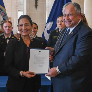 Secretary of the Navy Carlos Del Toro presents a sponsorship letter to Secretary of the Interior Deb Haaland during the ship-naming ceremony for the USS Ernest E. Evans.