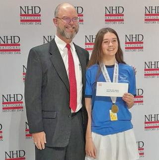 High school junior Claire Flynn, an avid participant in National History Day since she was in the sixth grade, poses with her Coskey Naval History Prize alongside  Chip Wallen, Chief Financial Officer of the U.S. Naval Institute, which now sponsors the prize.