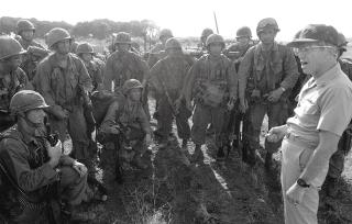 Vice Admiral Joseph Metcalf, commander of Task Force 120, speaks to a group of U.S. Army Rangers on the airfield at Point Salines during the multiservice operation.