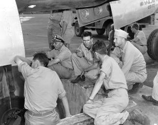 Parsons (right) supervises loading the Little Boy bomb into the B-29 Enola Gay.