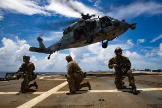 Explosive ordnance disposal personnel conduct a helicopter visit, board, search, and seizure exercise with an MH-60R Sea Hawk on board the Arleigh Burke–class guided-missile destroyer USS Dewey (DDG-105) in the Philippine Sea. 