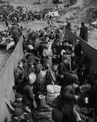 Civilians file aboard a U.S. Navy landing craft as thousands more jam the beaches awaiting evacuation to Taiwan, February 1955.