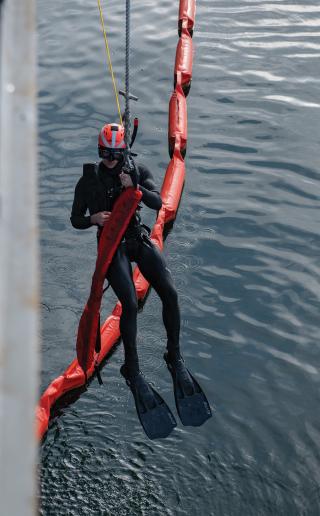 A search-and-rescue swimmer is raised onto the USS Chosin (CG-65). Some personnel redlines include a requirement for two rescue swimmers, without which ships may be unable to sail without flag approval.