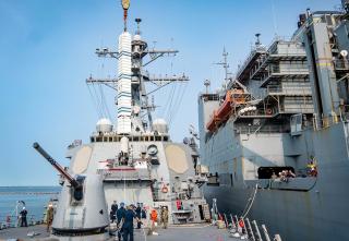 The Arleigh Burke–class guided-missile destroyer USS Porter (DDG-78) conducts a vertical launch system rearm event alongside Military Sealift Command dry cargo ship USNS William Mclean (T-AKE-12) during Large-Scale Exercise 2023. Reloading vertical launch cells at sea has long been deemed technically infeasible. But the capability may be coming to the fleet soon, after a series of experiments. 
