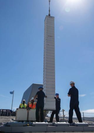 Sailors and Naval Air Station North Island weapon-systems personnel place a Tomahawk cruise missile into a silo