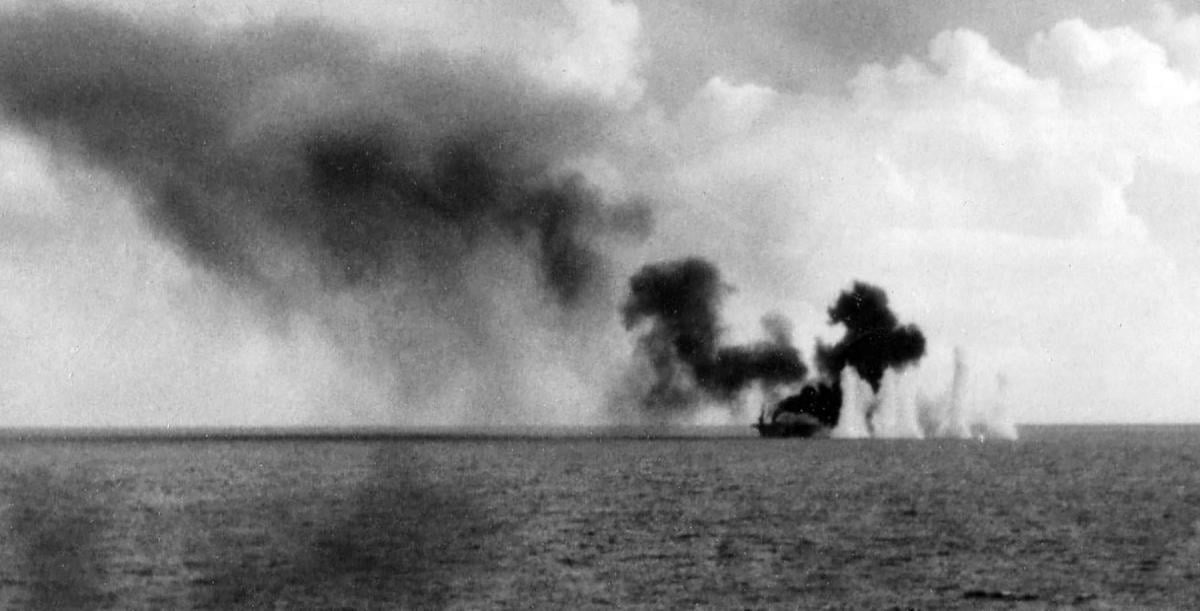 Shells from Japanese cruisers land near the burning escort carrier Gambier Bay during the Battle off Samar on the morning of 25 October 1944