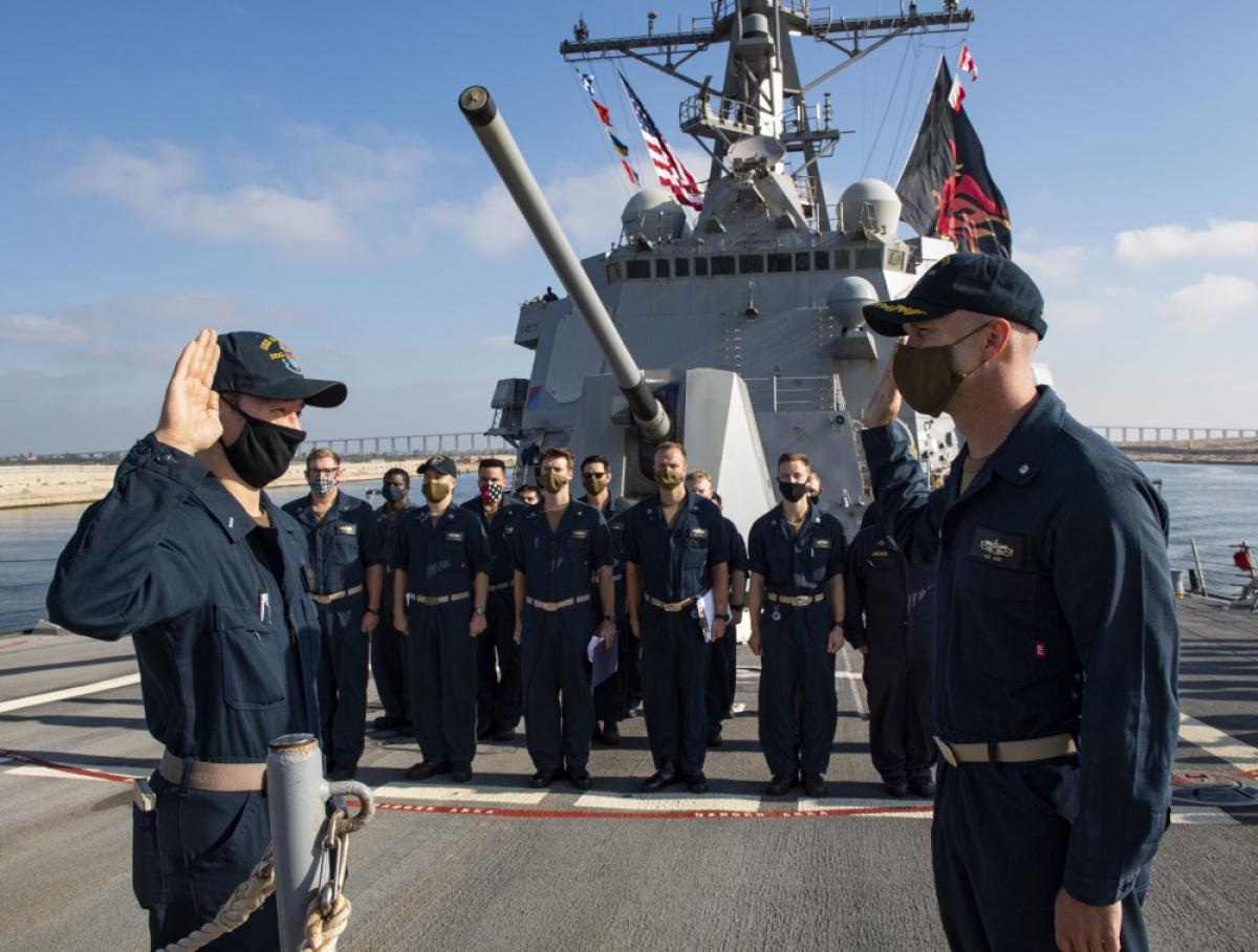 The commanding officer of the USS Sterett (DDG-104) administers the oath of office to an ensign during his promotion to lieutenant (j.g.).