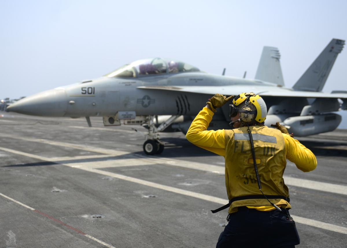 Aviation Boatswain's mate directs an EA-18G Growler, from the “Gray Wolves” of Electronic Attack Squadron (VAQ) 142, on the flight deck of the aircraft carrier USS Nimitz (CVN 68), July 25, 201