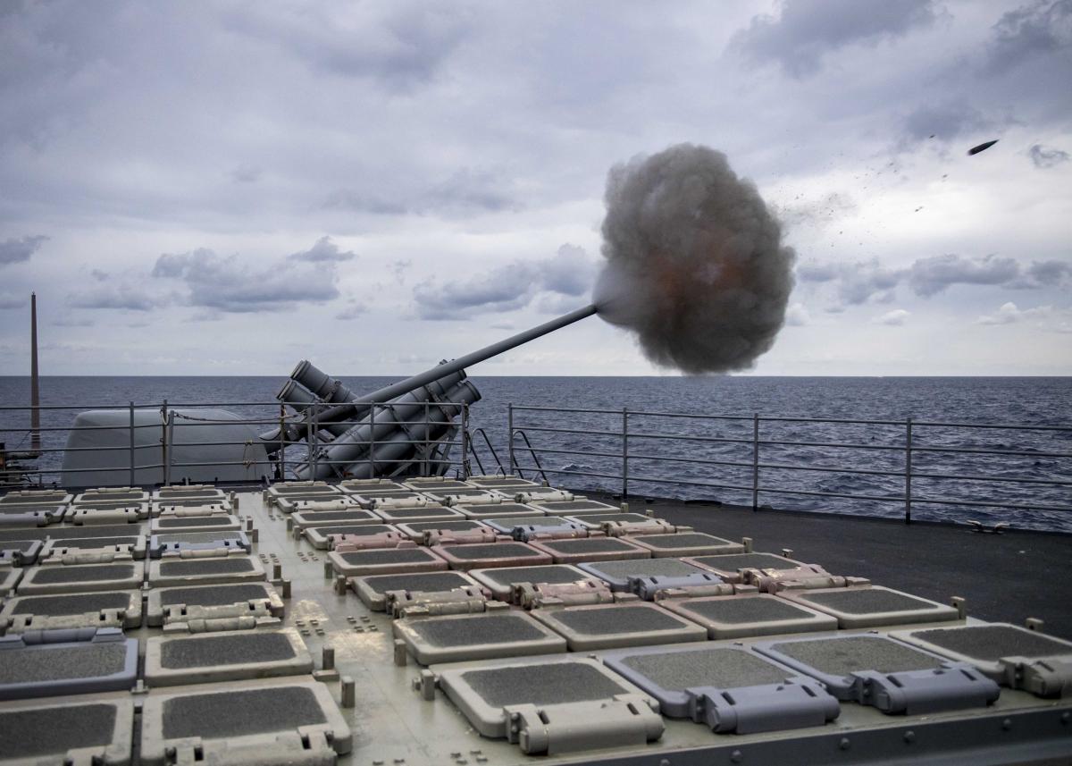 The Ticonderoga-class guided-missile cruiser USS Normandy (CG-60) fires its aft Mark 45 mod 4 5-inch gun during a live-fire exercise in the Mediterranean Sea. Cells from the ship’s Mk 41 vertical launching system are visible in the foreground.