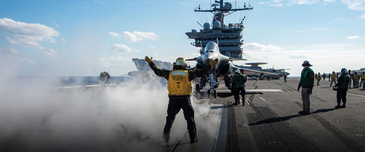 aviation handler directs the pilot of a French Rafale F-3R on the flight deck
