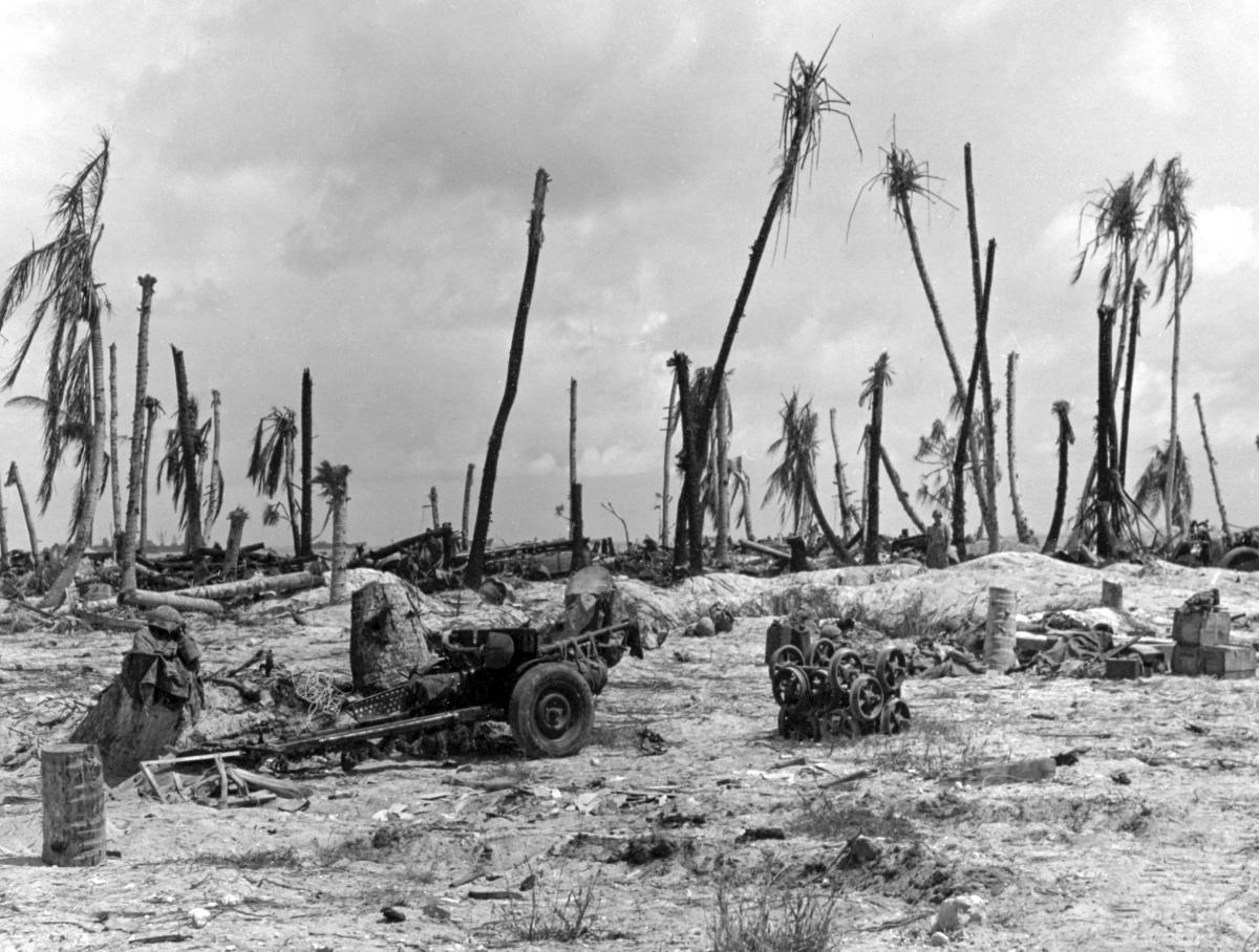 Marine packs and helmets hang from the barrel of a lone 37-mm gun on Tarawa