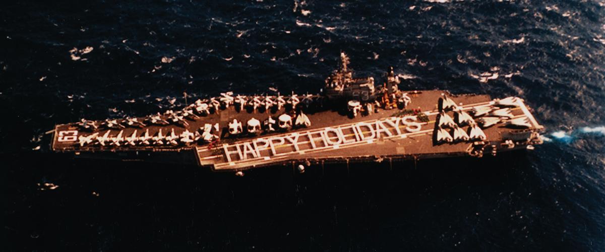 Nearly 2,000 sailors from the USS Kitty Hawk (CV-63) and Carrier Air Wing 15 wish the United States a “Happy Holidays” at the conclusion of their six-month western Pacific deployment on 14 December 1994.