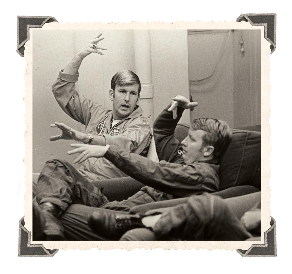 At Naval Air Station Oceana, Virginia, a Navy and Air Force pilot demonstrate a maneuver during a debriefing session after an air combat maneuvering mission. They are participating in a Joint Air Combat Tactics Training Program established to expose each service to the other’s air combat concepts (circa 1972). 