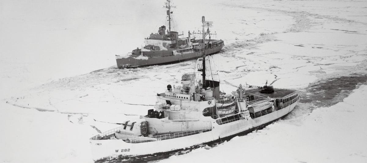 In this solid field of ice in the Bering Sea, two icebreakers try a tandem method of breaking ice. Ramming, backing, and ramming again, the vessels try forcing their way, side-by-side, in a parallel line.