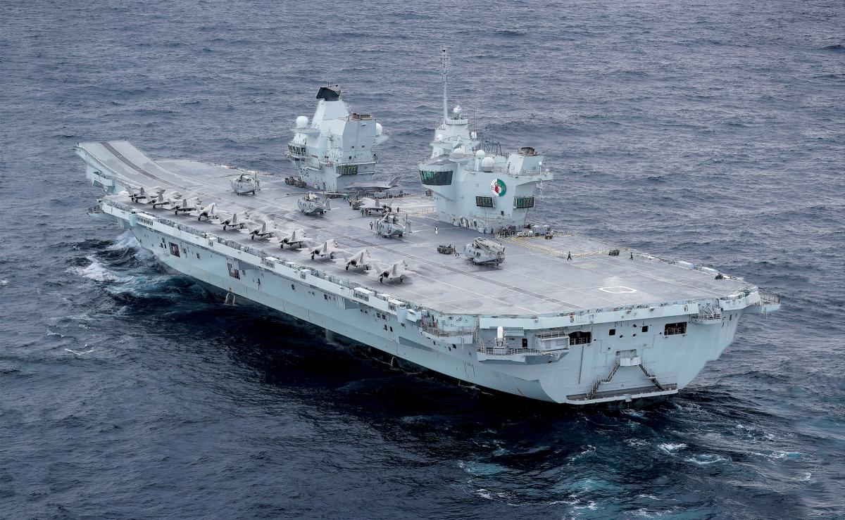 HMS Queen Elizabeth under way during training exercises in October 2020.  A dozen F-35B strike fighters  and four Merlin  naval helicopters  are visible on the flight deck.